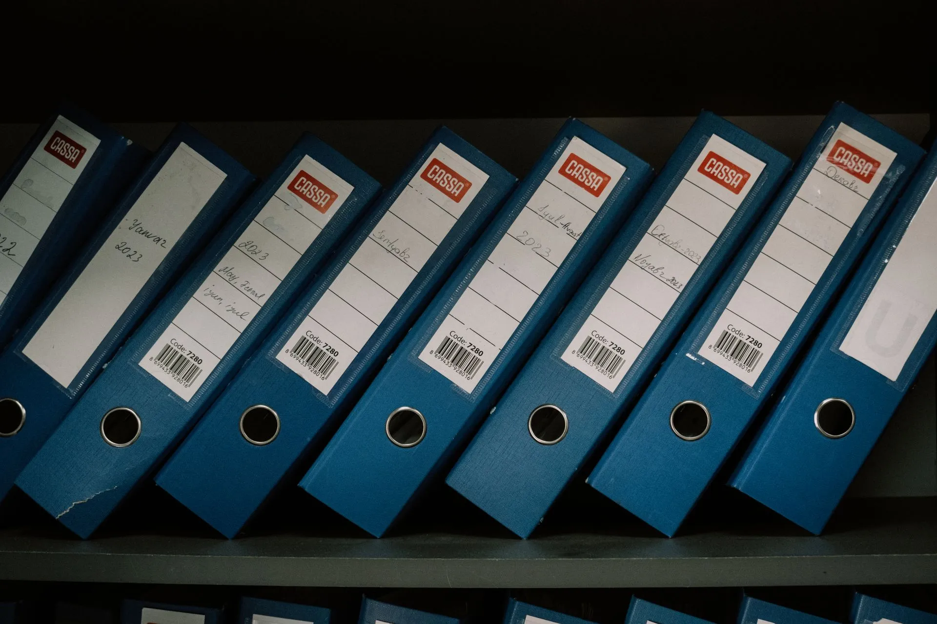 Reihe beschrifteter Ordner mit Datumsangaben in einem Archivregal