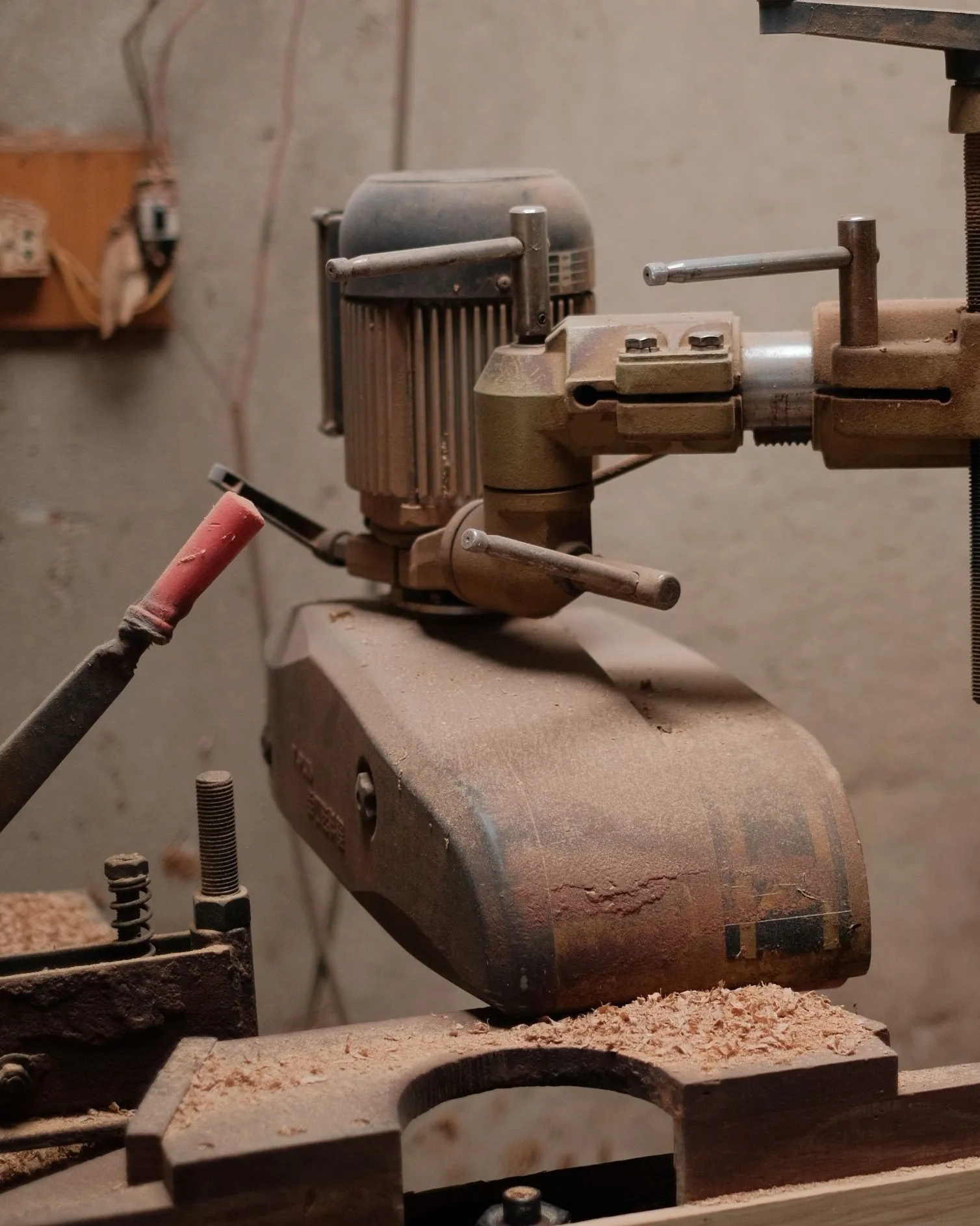 Mit Holzstaub zugesetzter Elektromotor einer Holzbearbeitungsmaschine, daneben eine offene Verteilerdose an der Wand